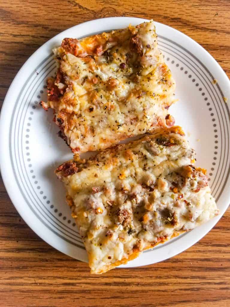 school sausage pizza on a plate on a brown table. 