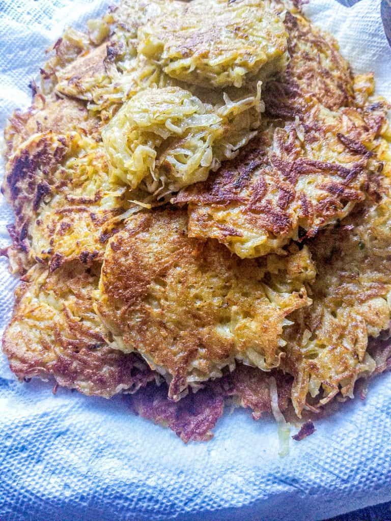 cheesy hasbrowns stacked on a plate with a paper towel under. 