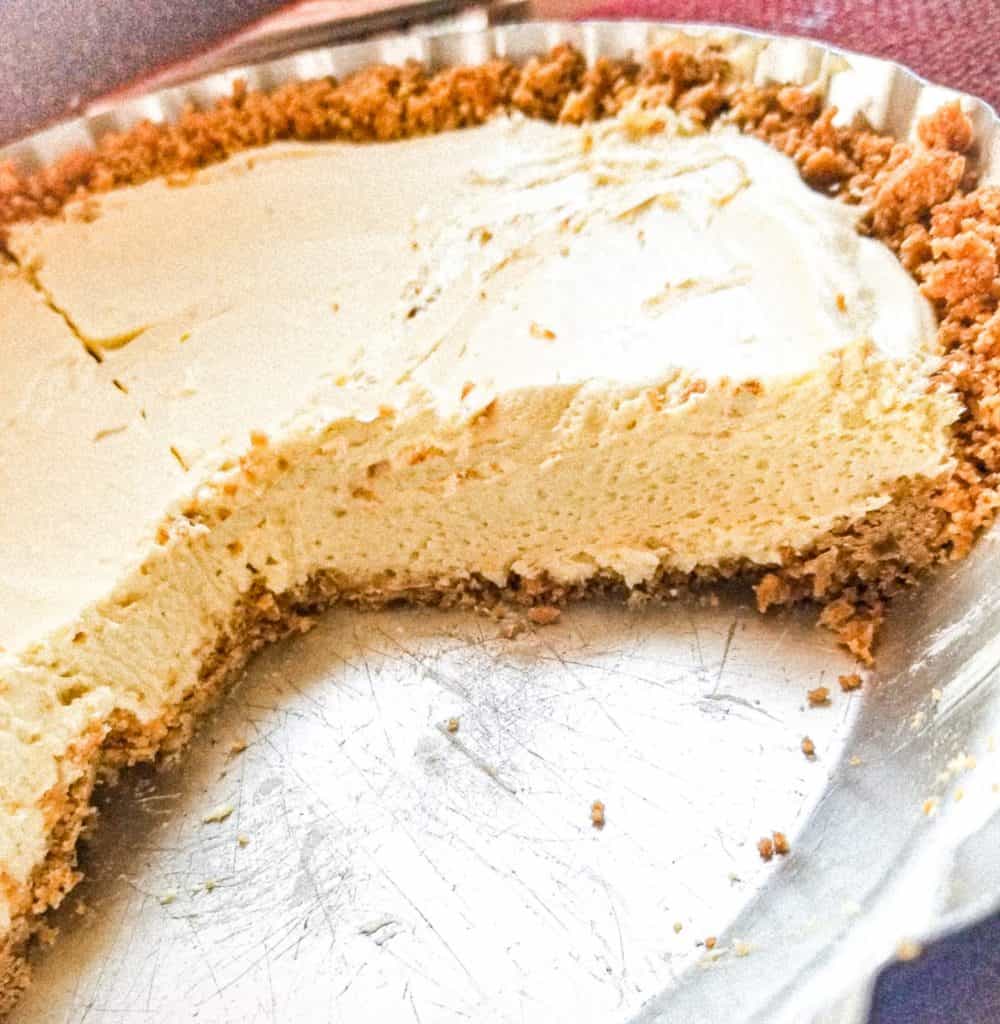 lemon cheesecake pie in a pan with a piece taken out. 