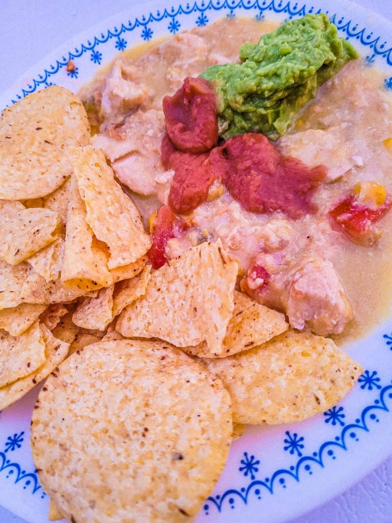 slow cooker chicken enchilada dip on a plate with chips. 