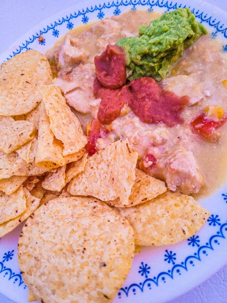 slow cooker chicken enchilada dip on a plate with chips.
