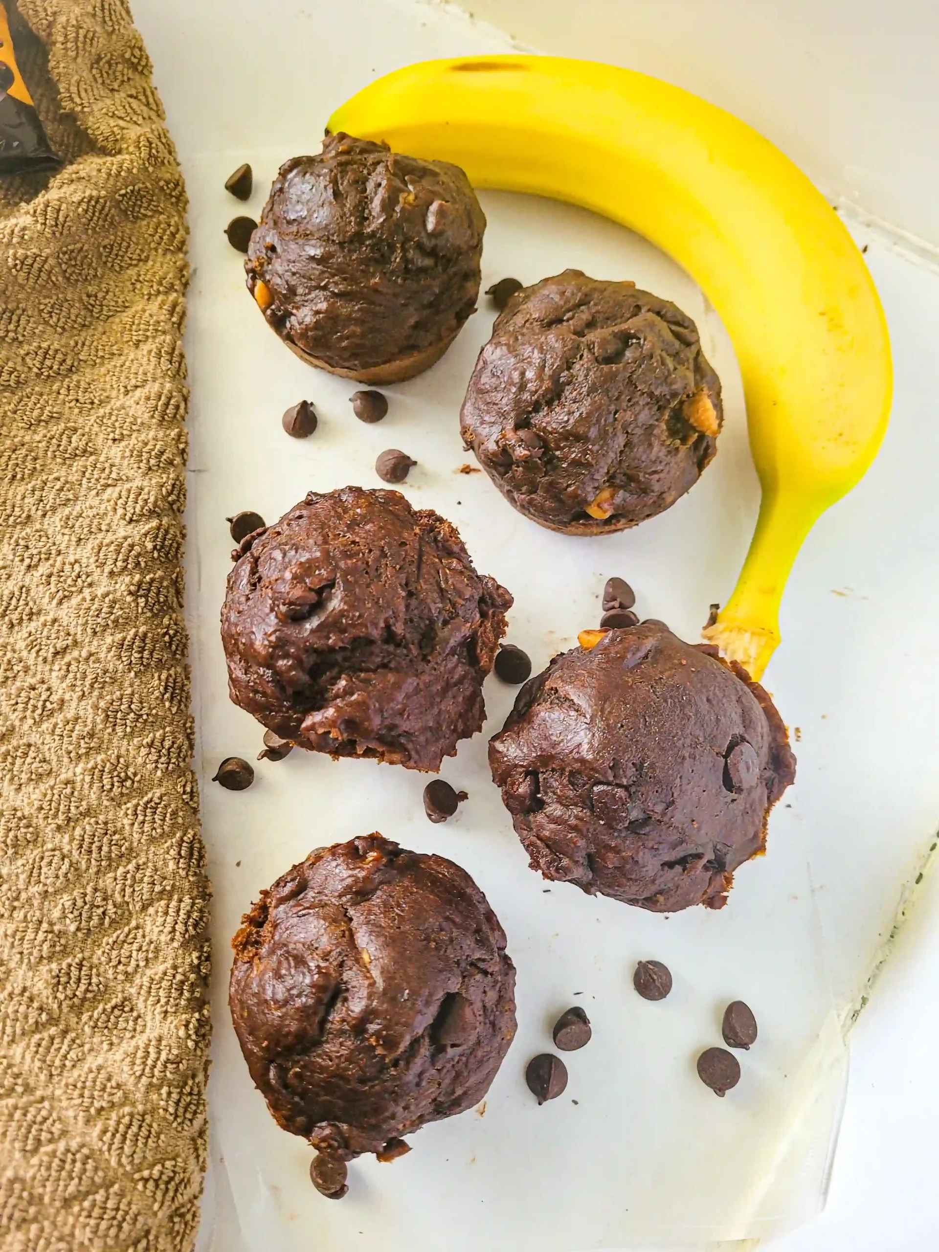 top view of banana chocolate chip muffins with towel on the left side.