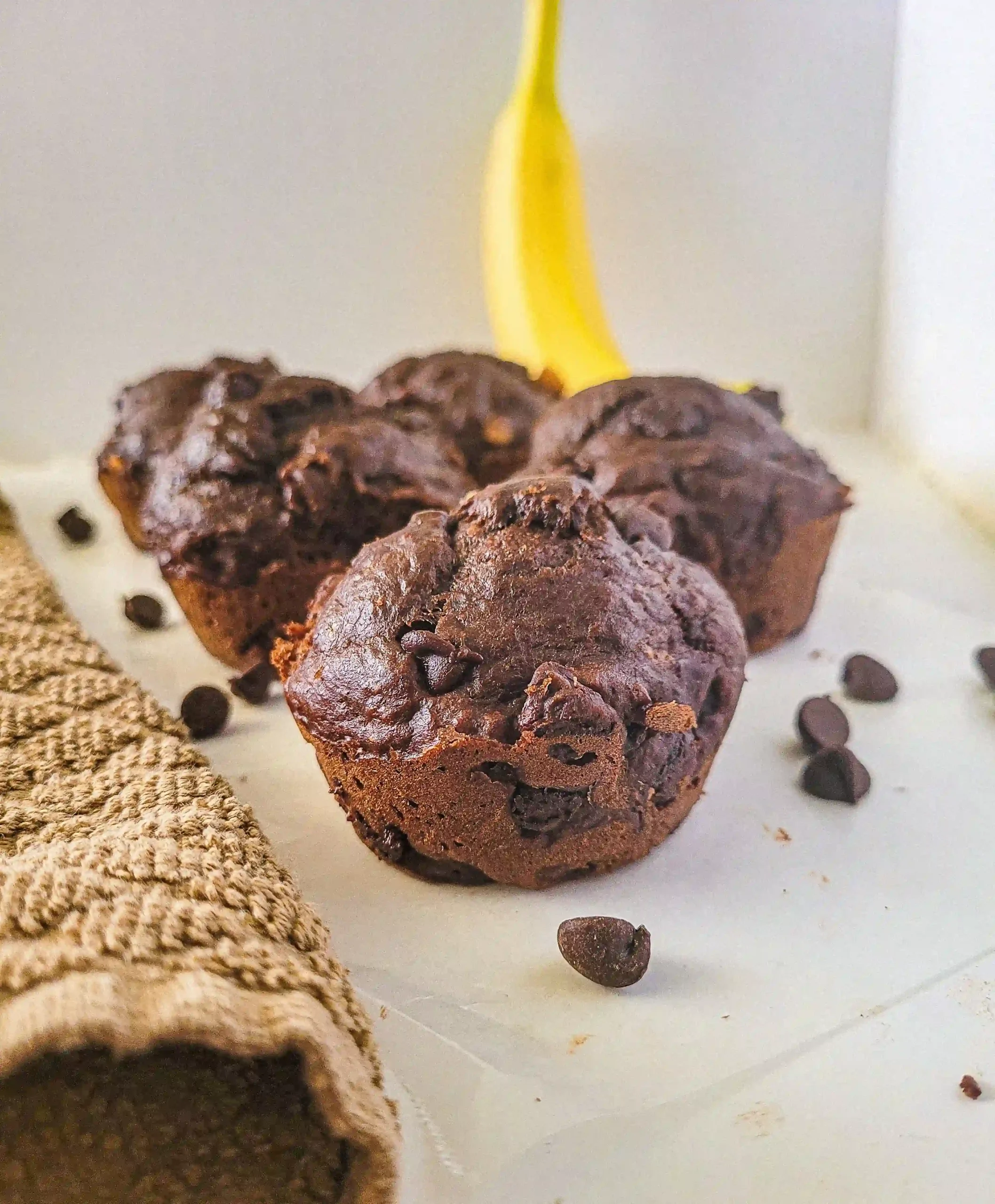 close up of double fudge banana muffin with banana in back.