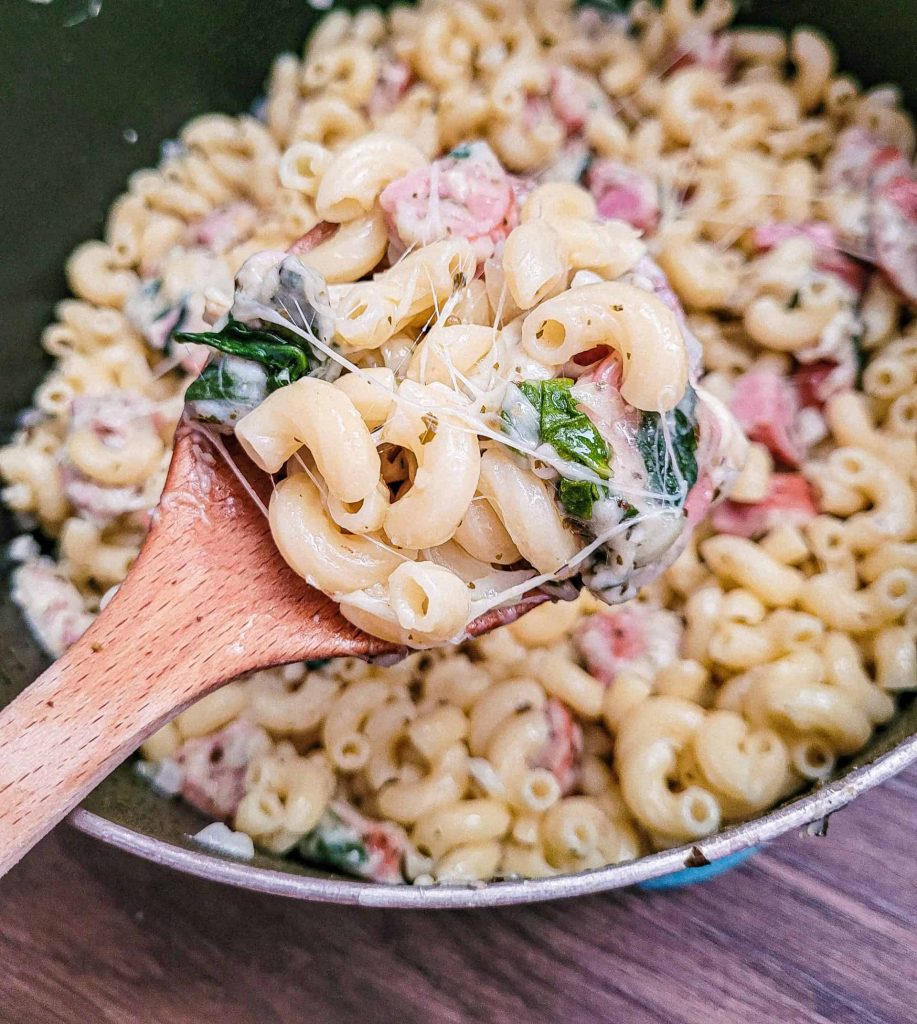 spinach and sausage pasta on a spoon. 