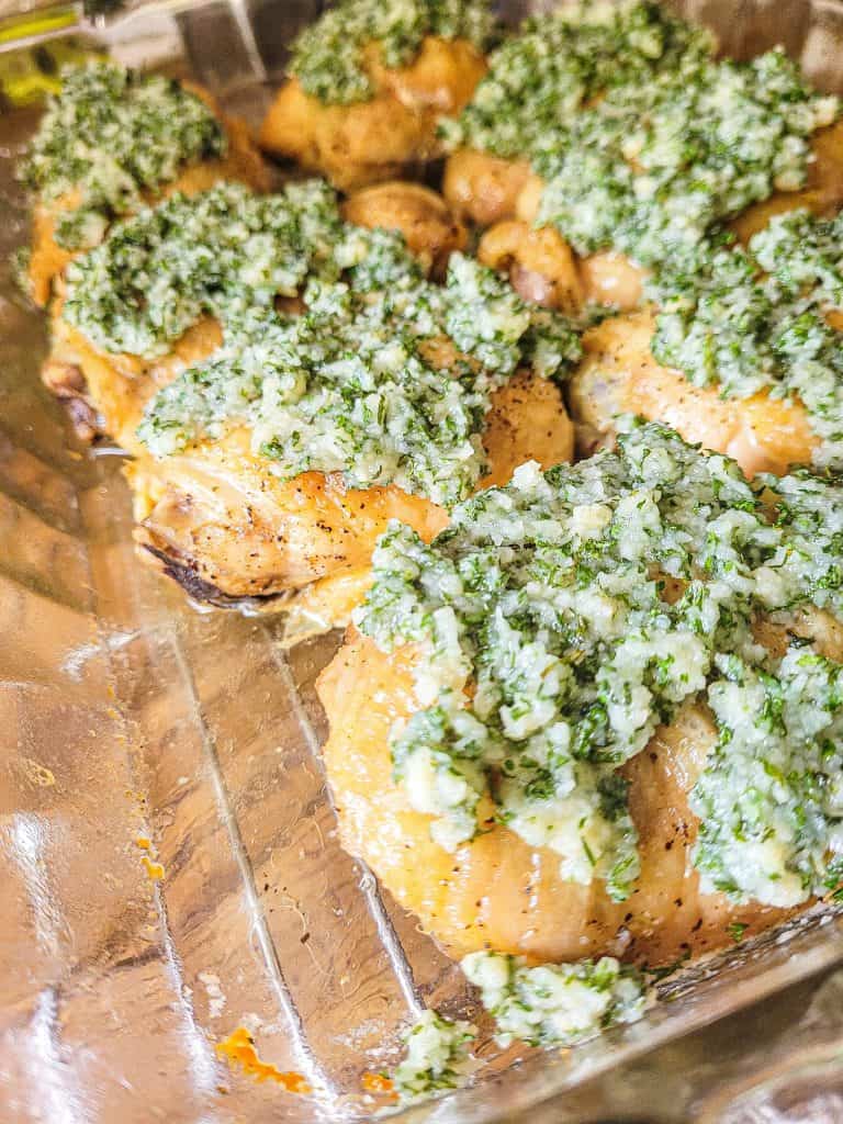 garlic parmesan chicken thighs in a glass baking dish at a side angle.