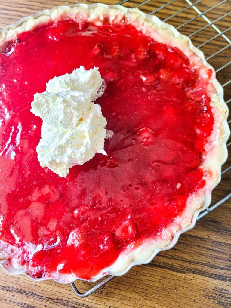 Fresh strawberry raspberry pie with jello on in a pan on a wire rack. 