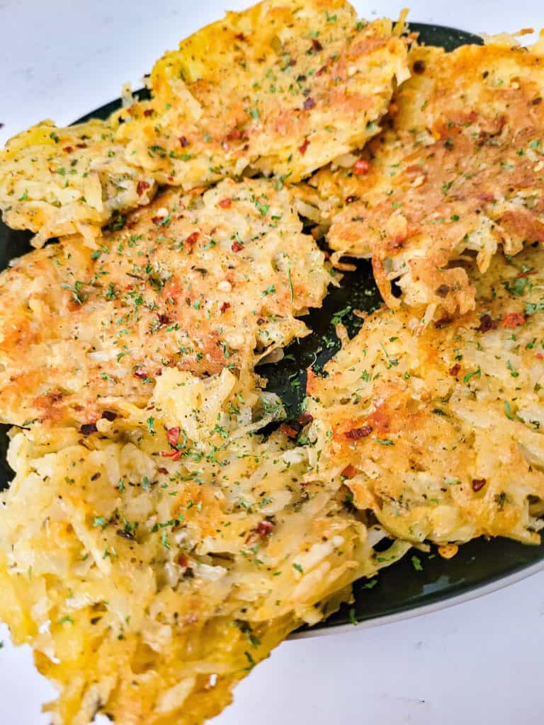 hashbrown patties on a black plate with a white background. 