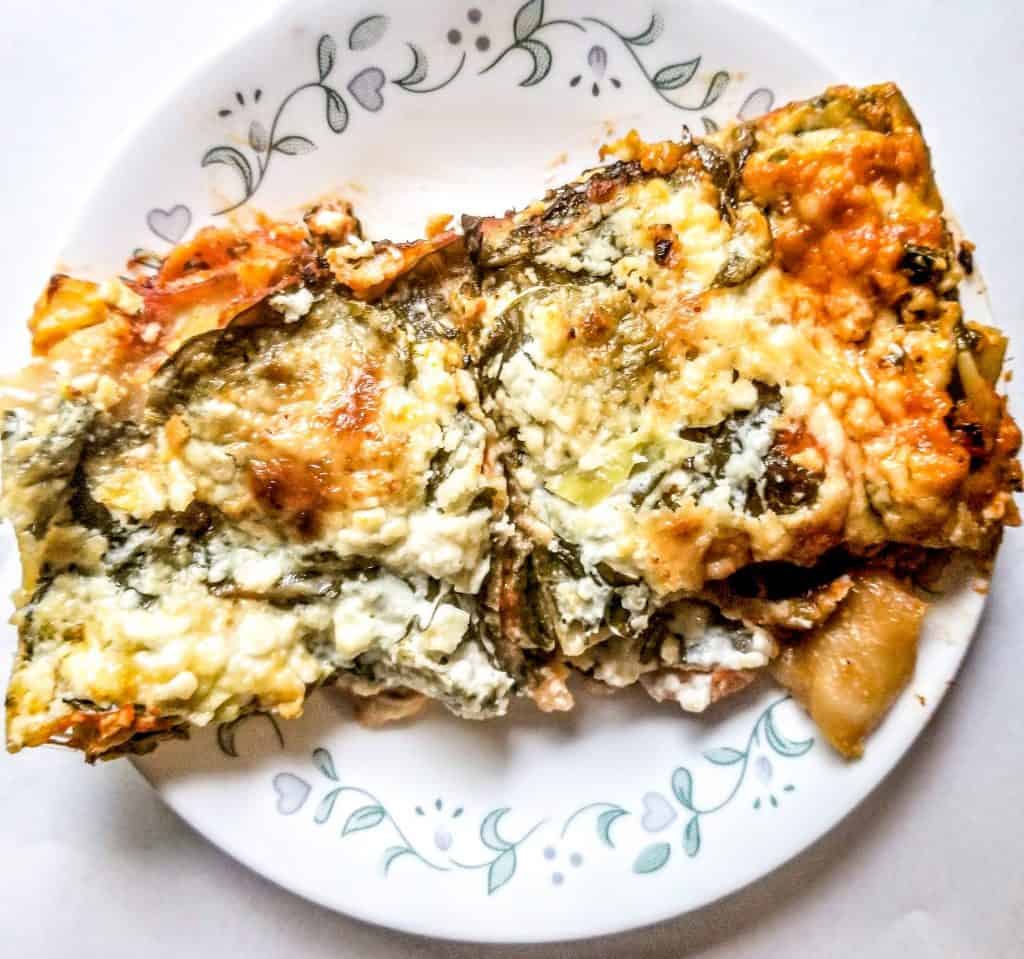 spinach and artichoke lasagna on a white plate.