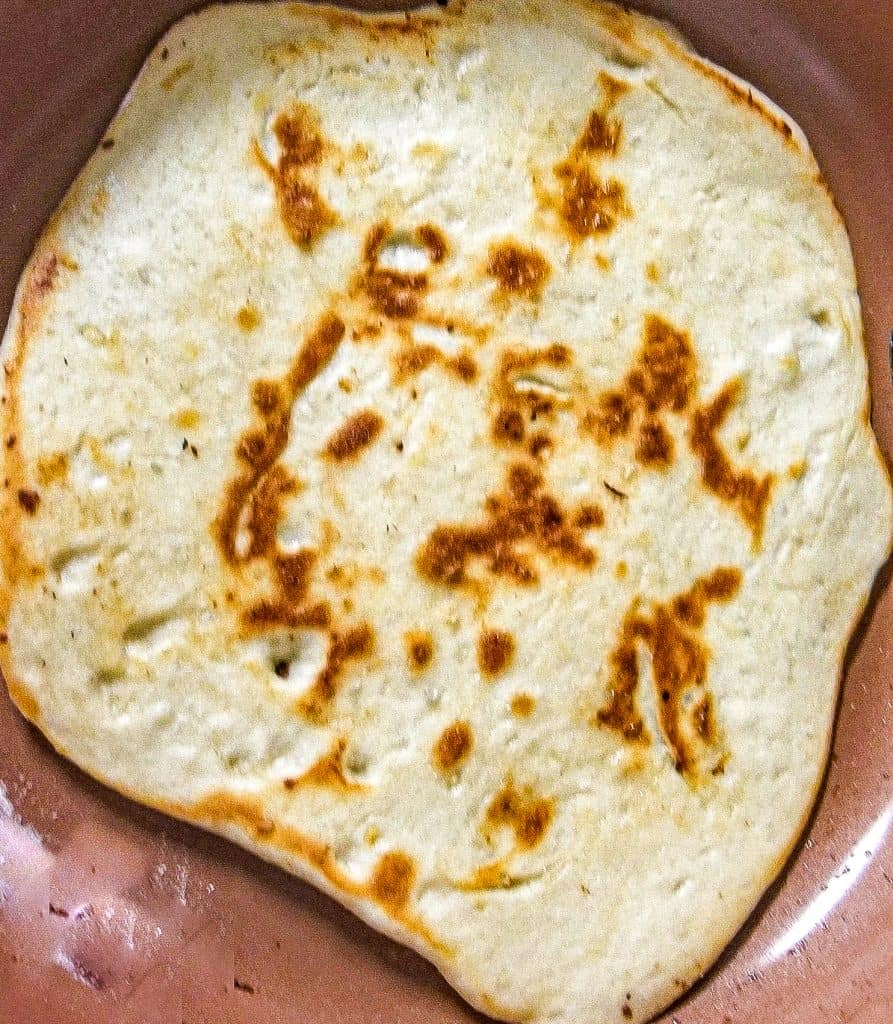 cooked naan no yogurt in a brown pan. 