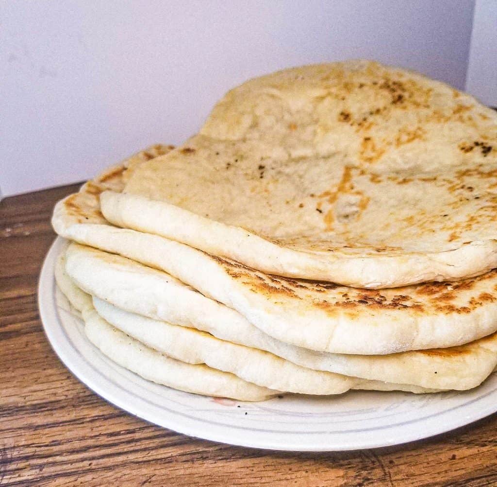 vegan naan bread stacked on a plate. 