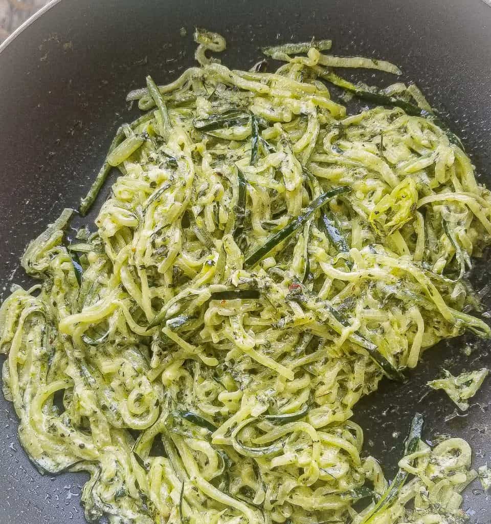 creamy pesto zoodles in a black skillet.