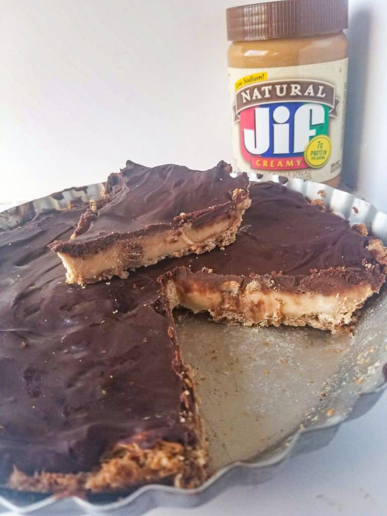 peanut butter cup cheesecake with jar of peanut butter in the background. 