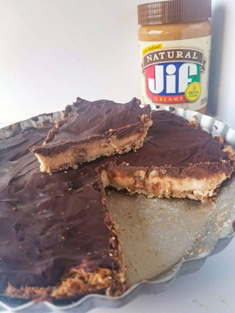 peanut butter cup cheesecake with jar of peanut butter in the background.