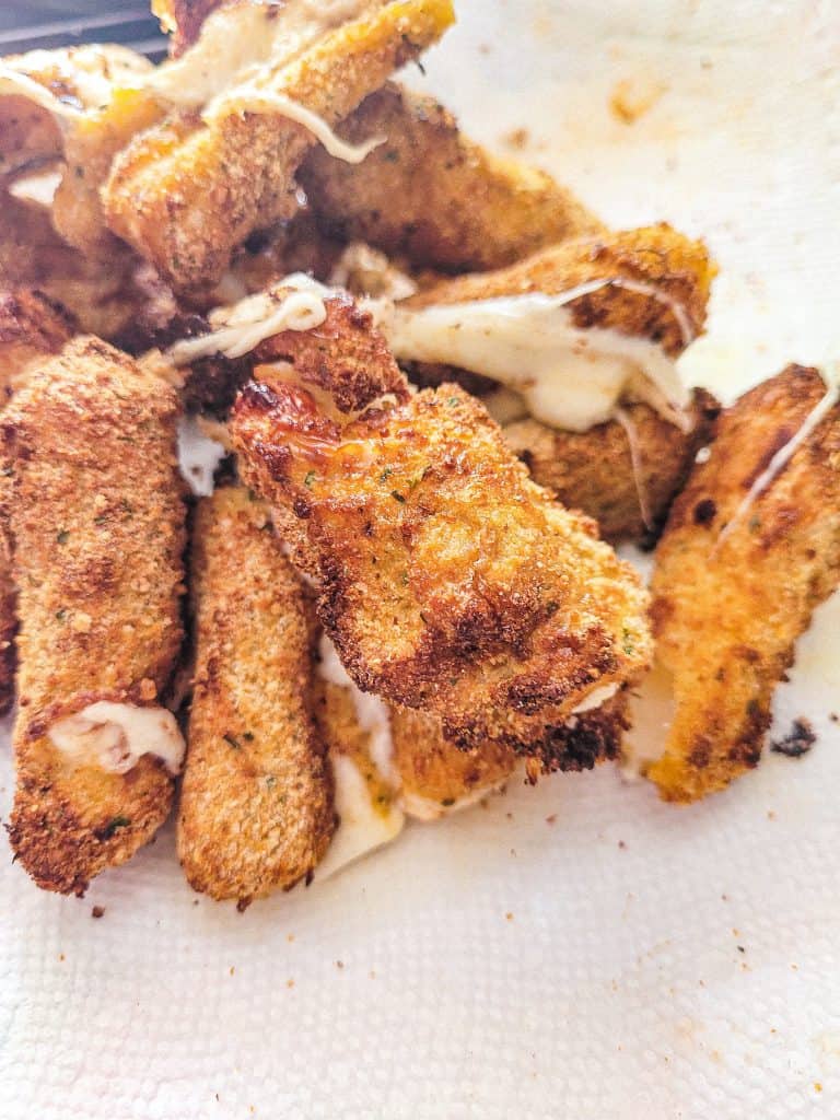 baked mozzarella cheese sticks on a paper towel.
