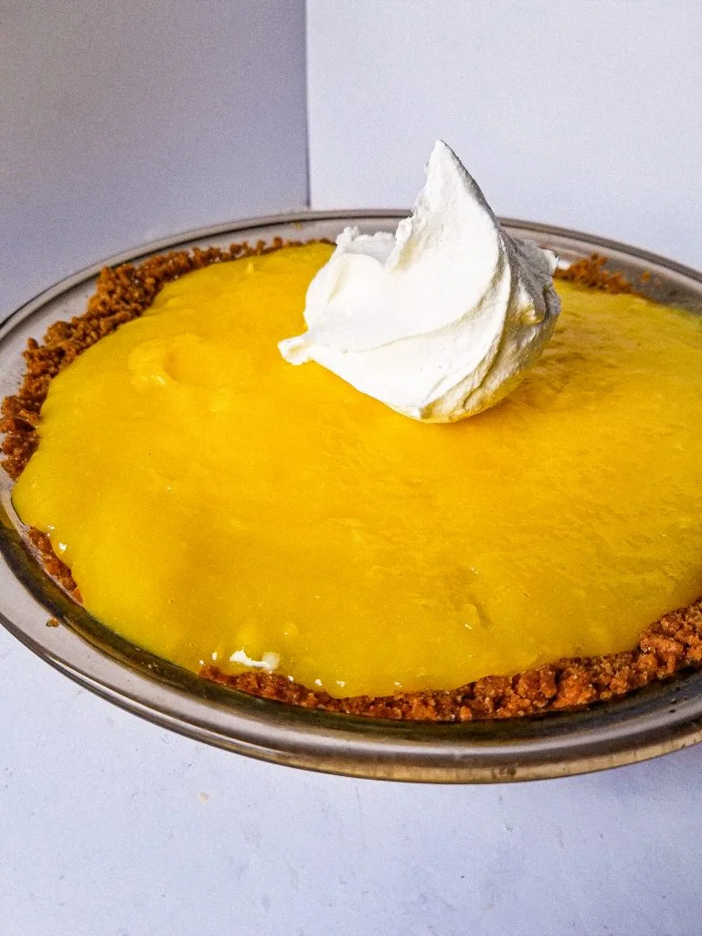 easy lemon pudding pie side view with whipped cream on top. 