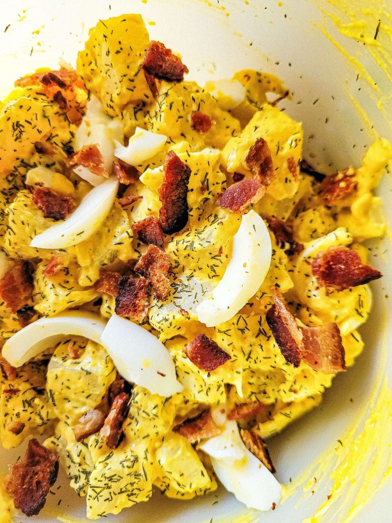 deviled egg potato salad close up in a clear bowl. 