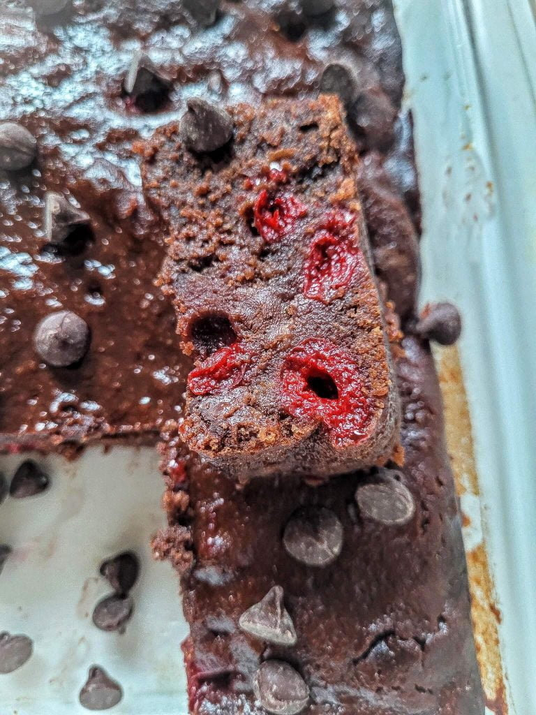 cherry brownies with a slice on top in a glass pan. 