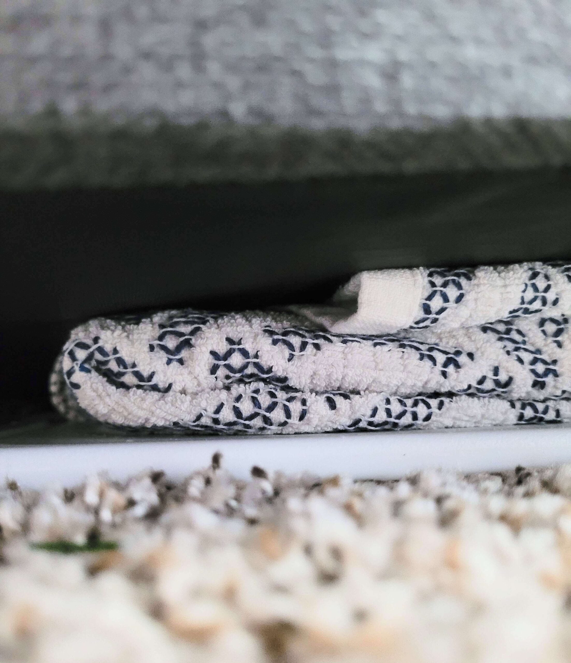 tofu wrapped in towel placed on a cutting board on the carpet being pressed by a box of shoes.