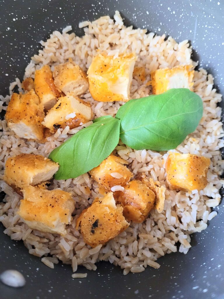 buffalo tofu in a pot with basil leaves on top and rice below. 