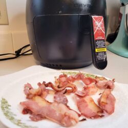 Bacon on paper towel with air fryer in background.