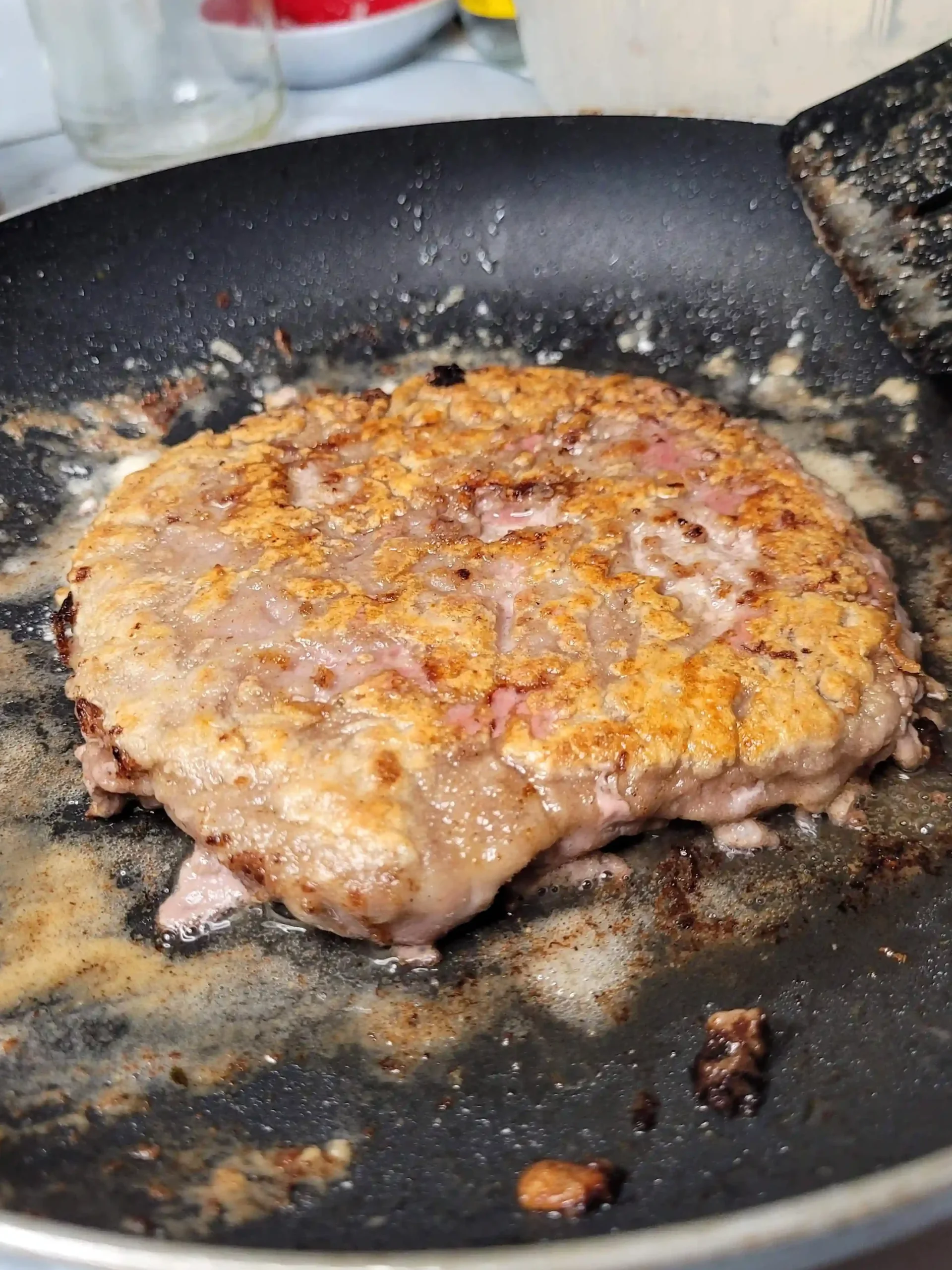 crispy floured steak cooking in skillet.