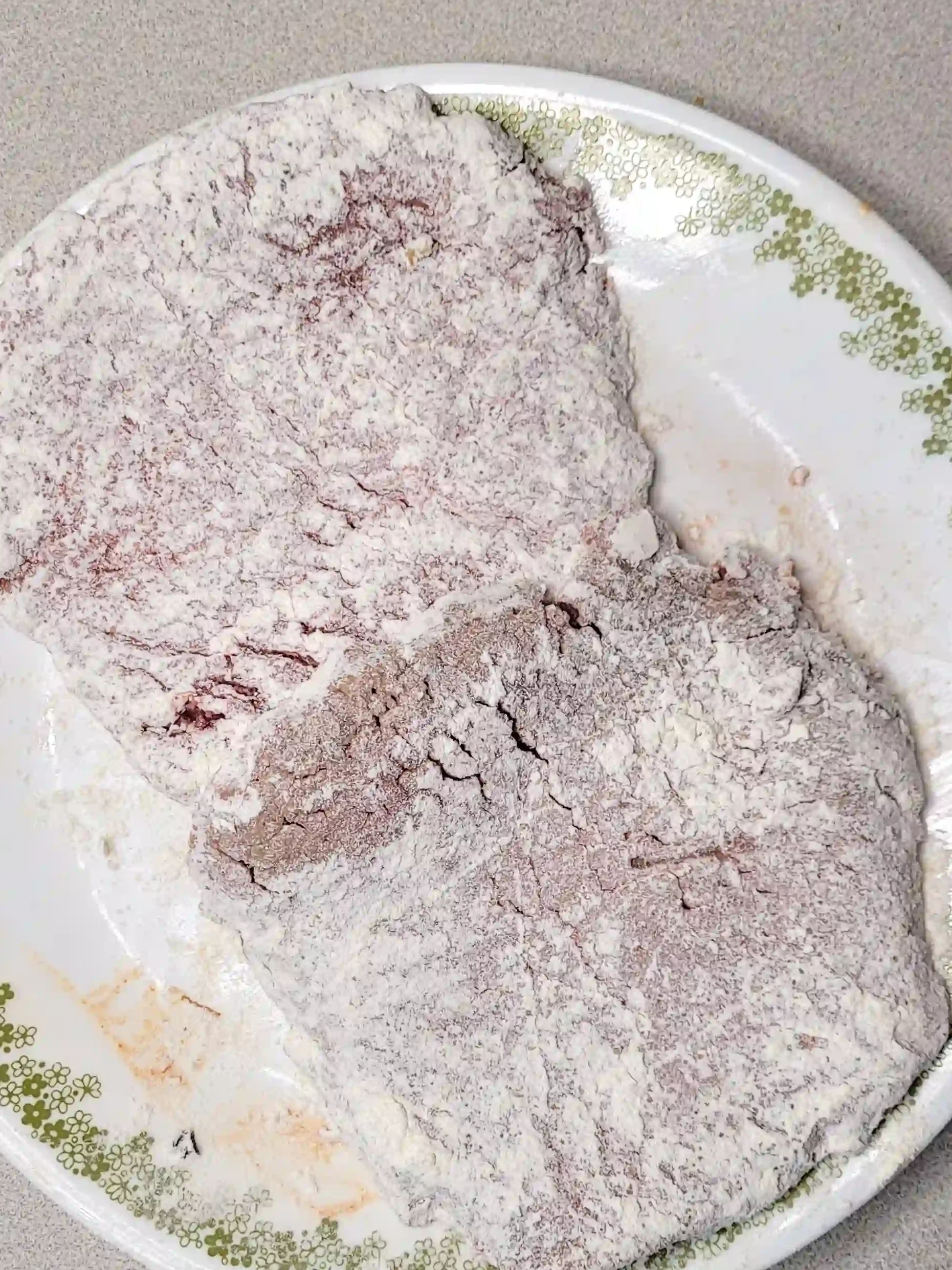 floured steak resting on plate.