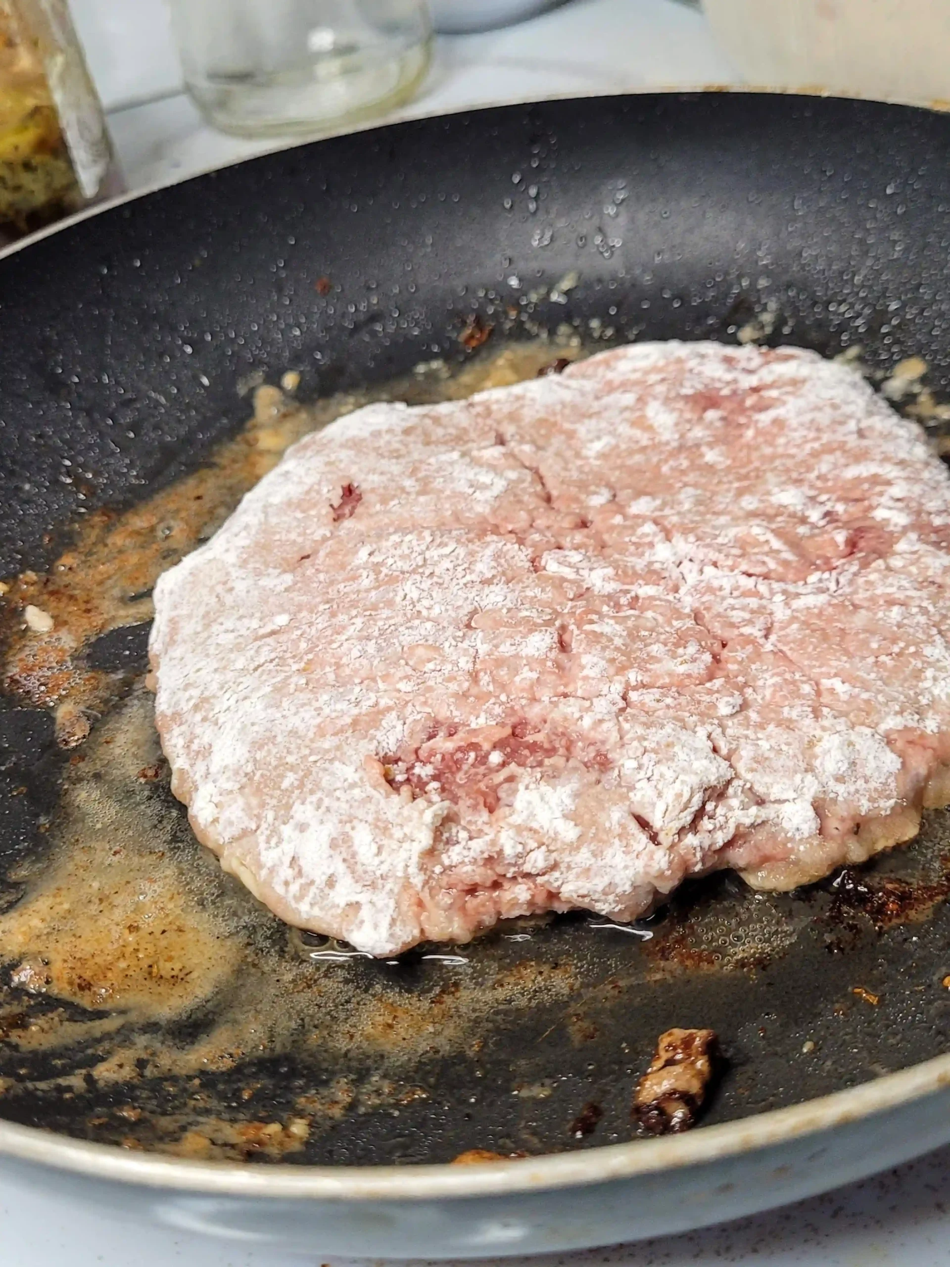 raw cube steak cooking in black skillet.