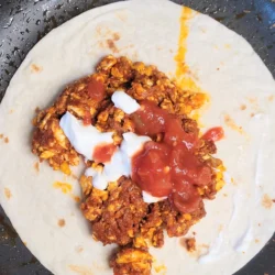chorizo and egg tacos top view with sour cream and salsa.
