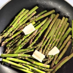 Frying asparagus with garlic butter on top.