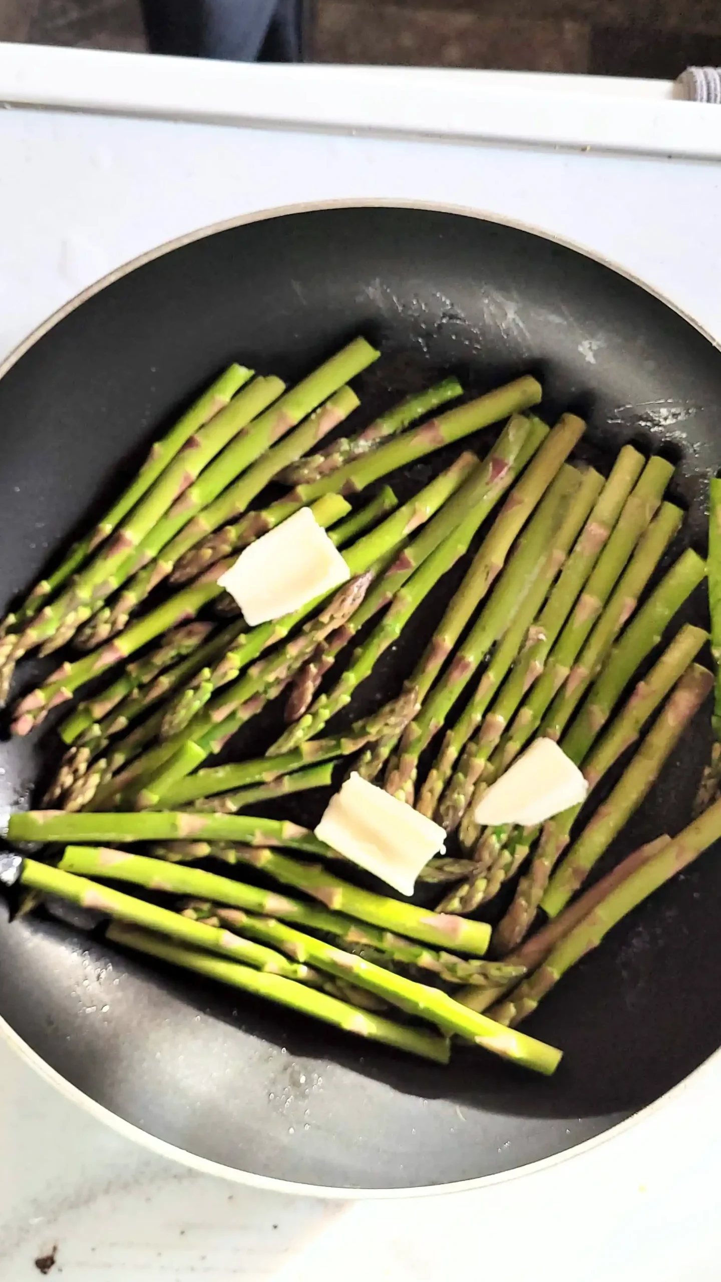 Frying asparagus with butter on top.