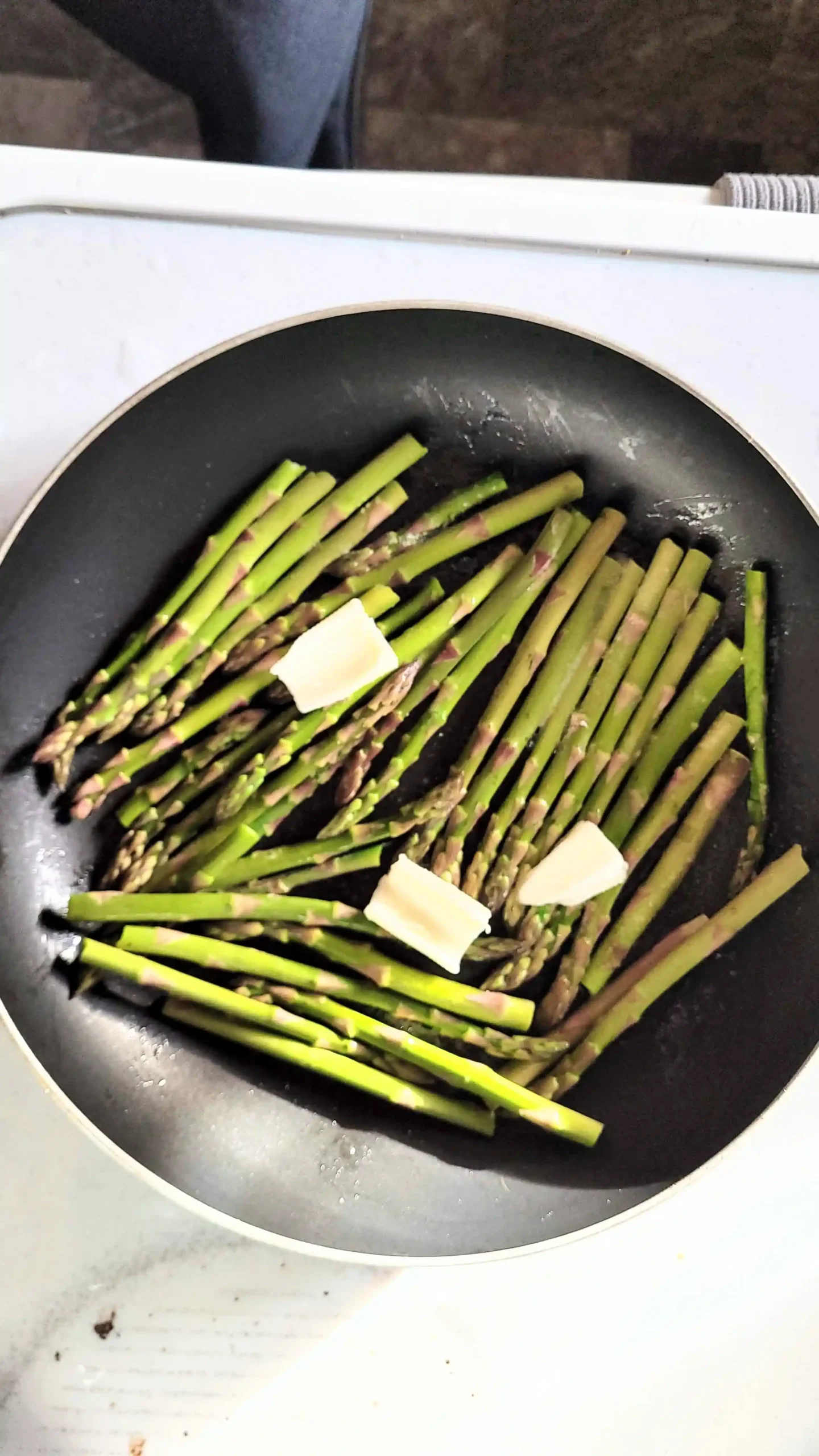 Frying asparagus with butter on top.