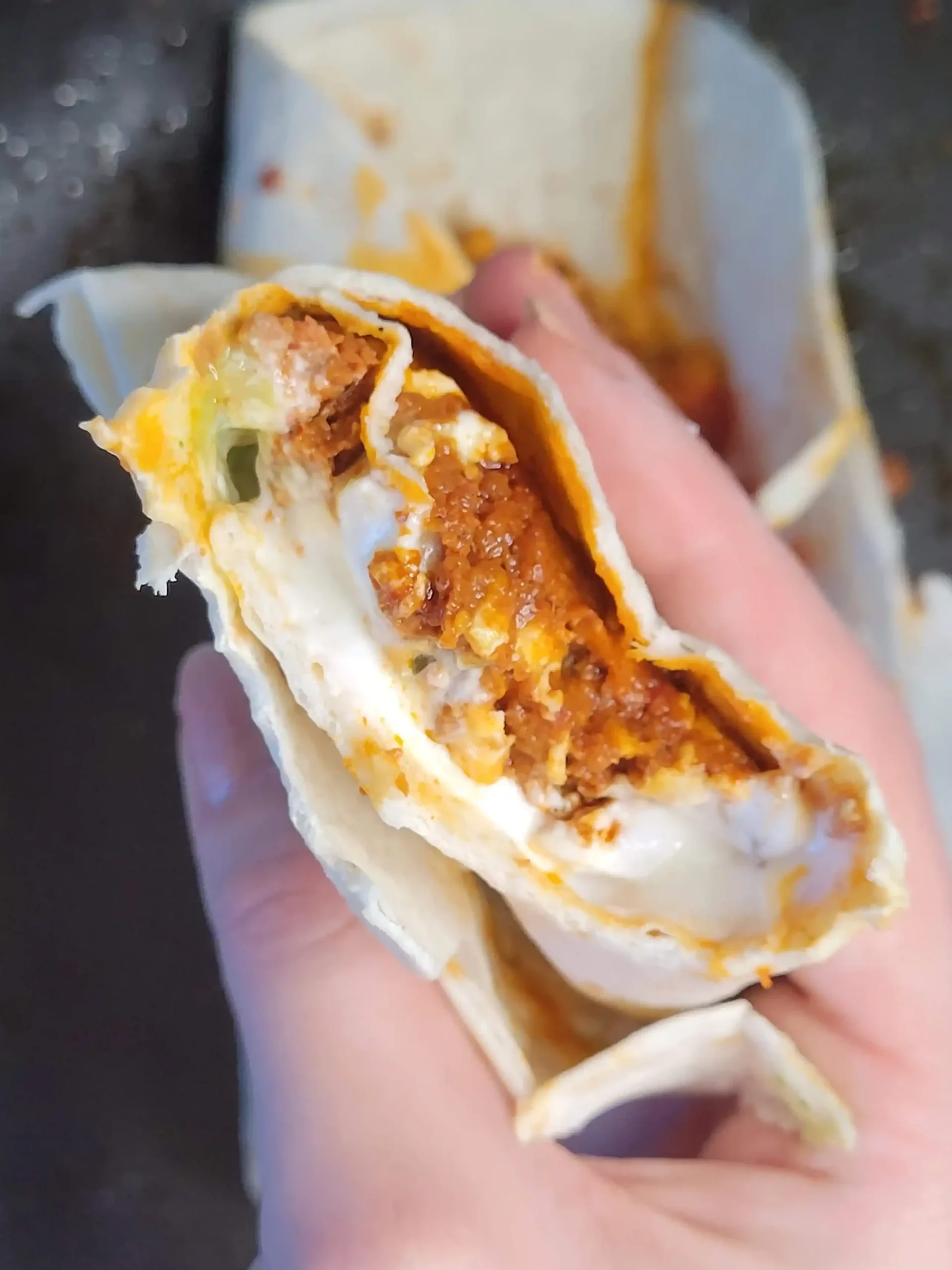 partially eaten chorizo taco with hand holding it.