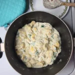 alfredo tortellini with spoon in background.