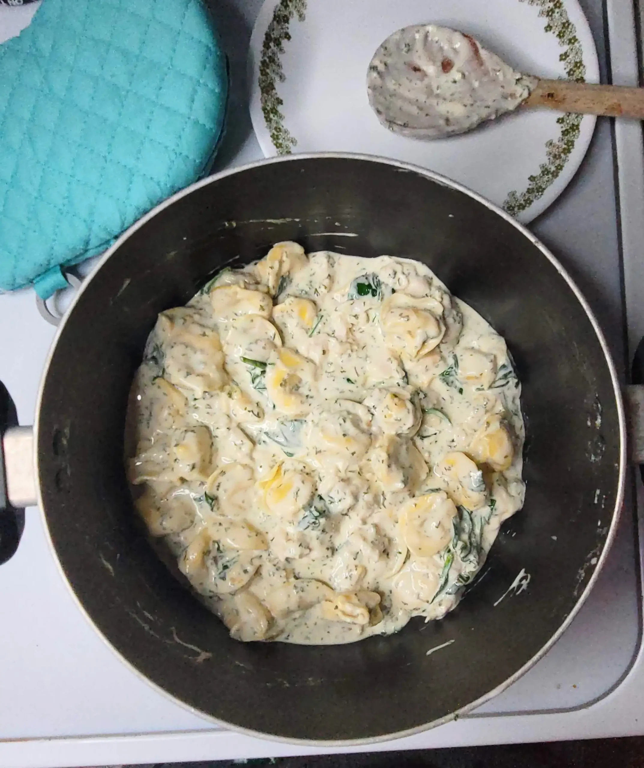 tortellini alfredo with spoon in background.