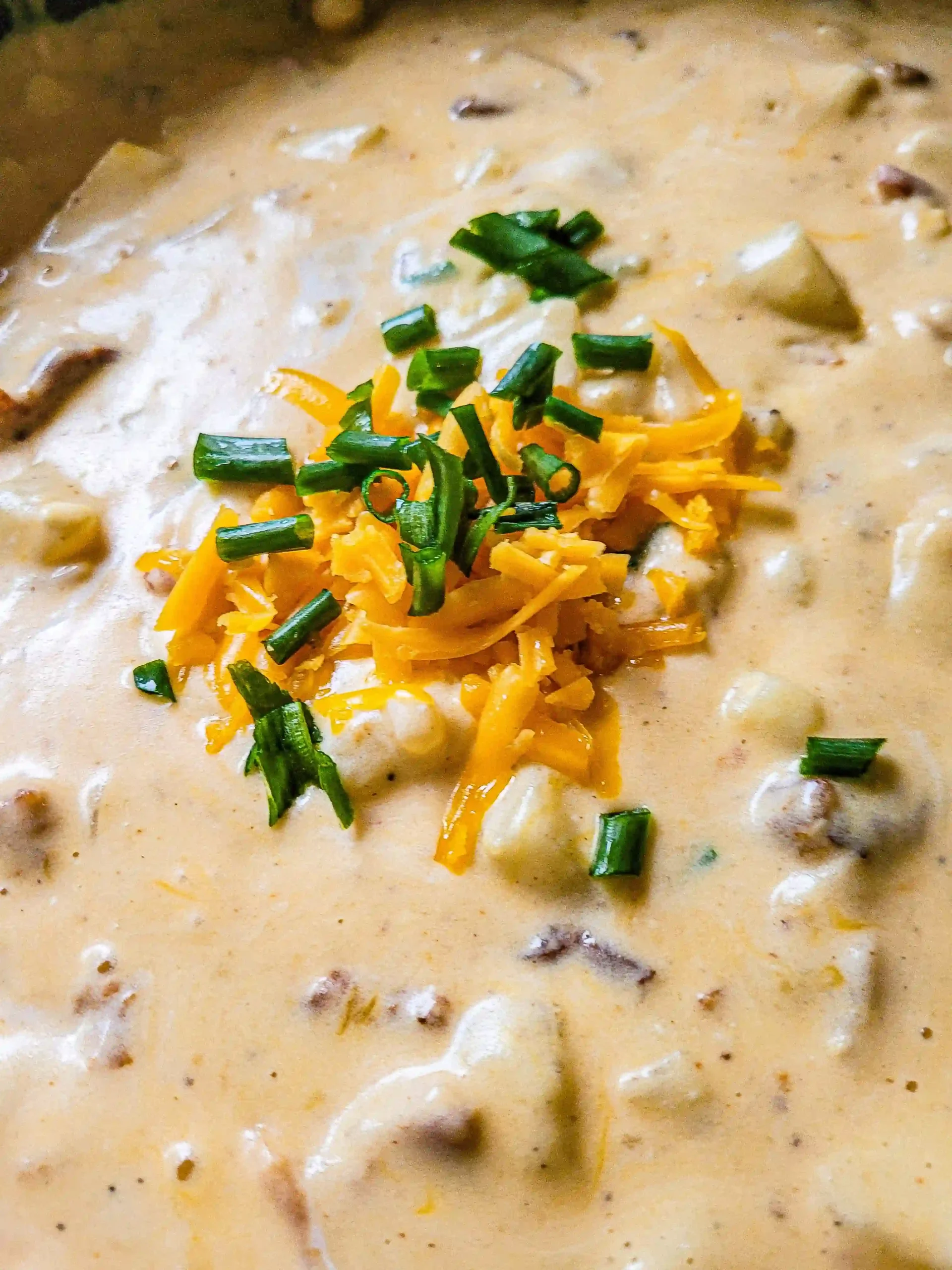 potato soup with scallions and cheese on top.