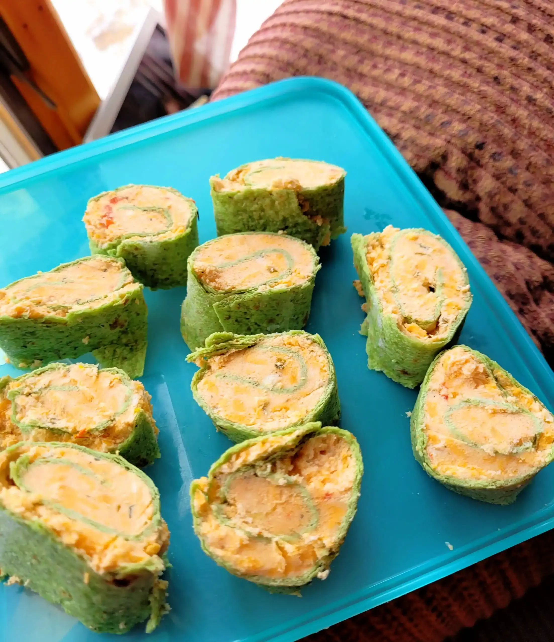 pinwheel sandwiches with green tortillas on blue plastic.